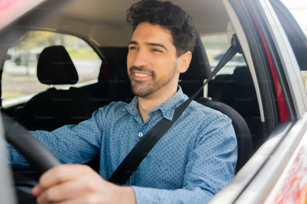 Hombre sonriendo mientras conduce un coche.