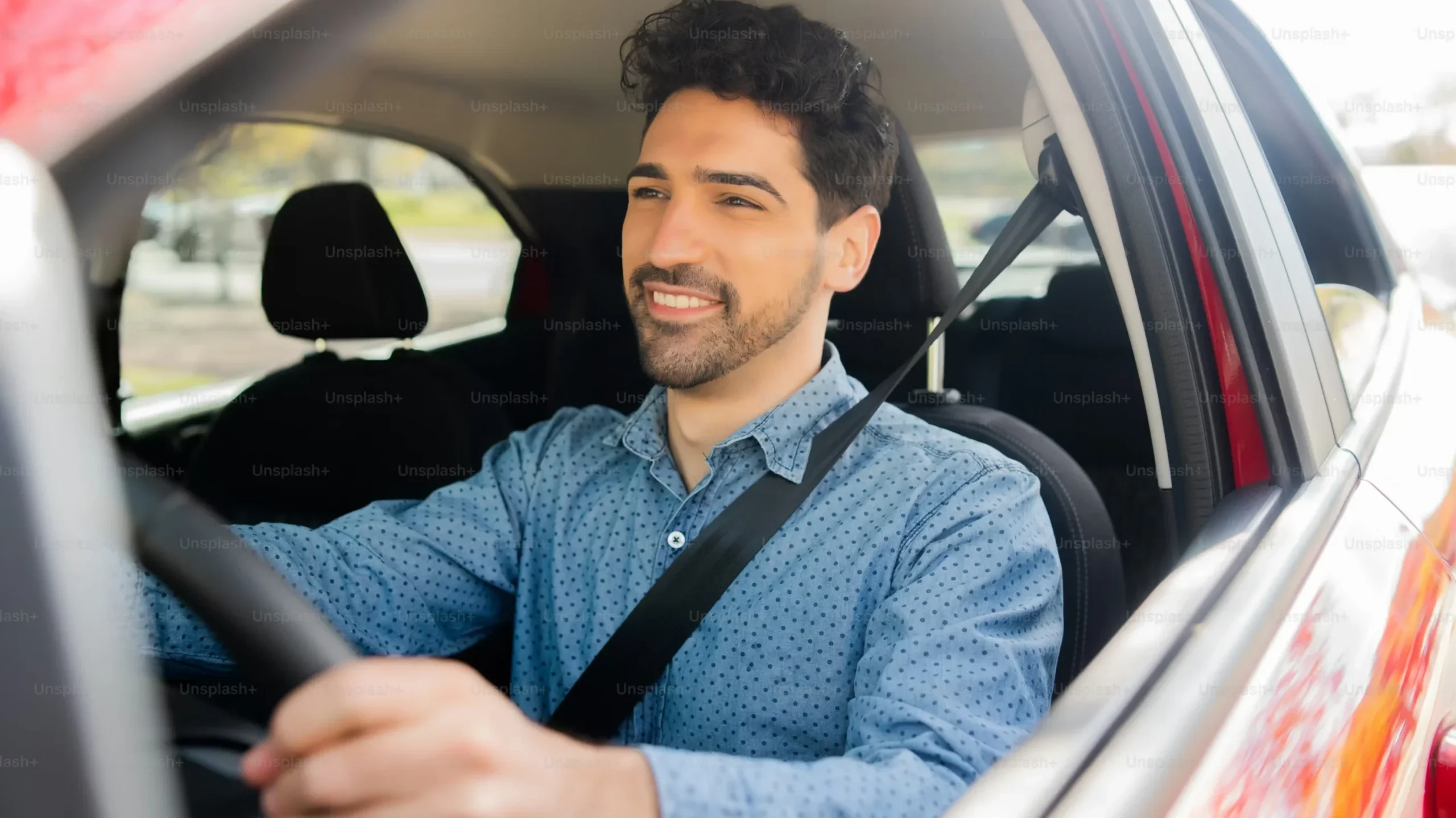 Hombre sonriendo mientras conduce un coche.