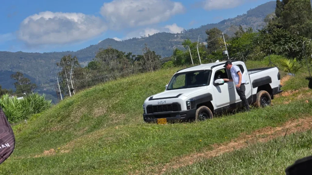 negocio corporativo de Kia: Camioneta Kia Tasman blanca en terreno irregular con persona.
