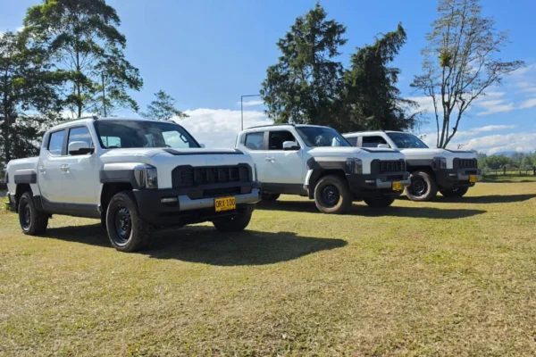 negocio corporativo de Kia: Tres camionetas Kia Tasman blancas en un campo.