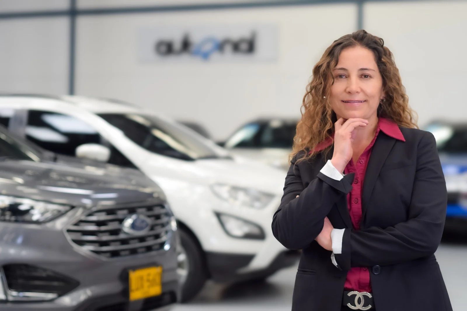 aniversario de Autonal: Ejecutiva de Observauto posa junto a vehículos de exhibición.