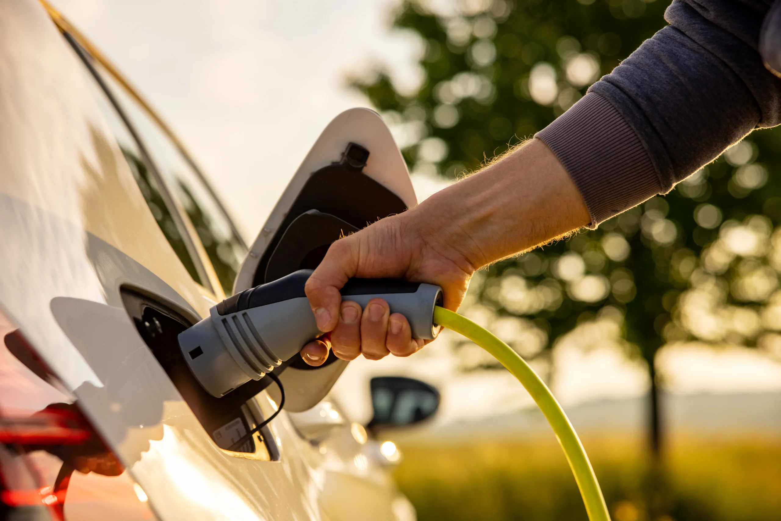 sostenibilidad de Astara: Persona conectando cargador a vehículo eléctrico.