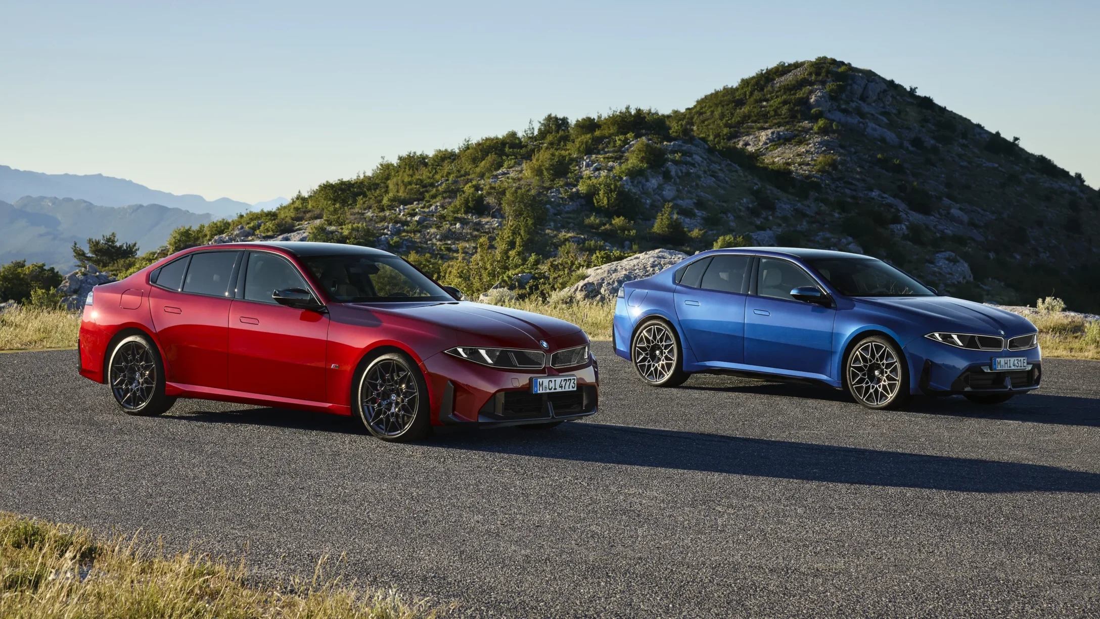 BMW Serie 3: BMW i4 M50 rojos y azules en carretera montañosa.