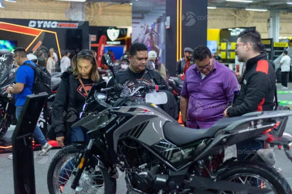 Expo2Ruedas 2026: Personas viendo motocicleta SYM NH-T 150 en feria.