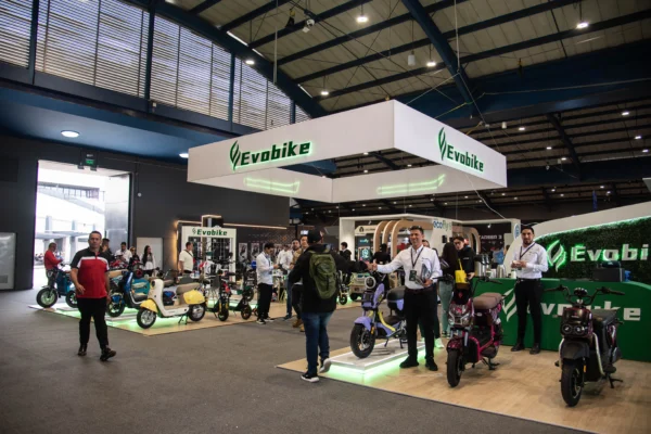 movilidad alternativa Expo2Ruedas: Visitantes en un evento de movilidad eléctrica con scooters y bicicletas.