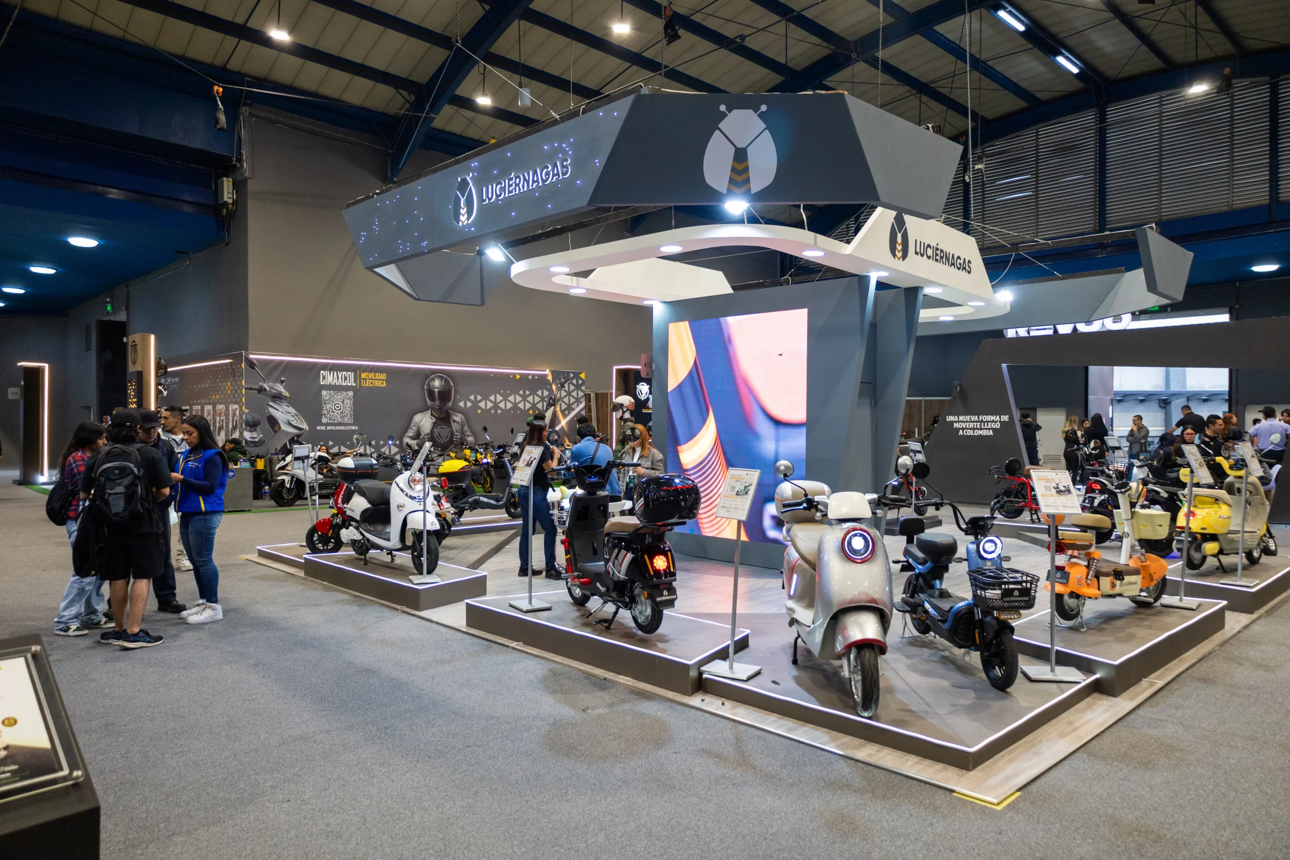 movilidad alternativa Expo2Ruedas: Personas observando scooters eléctricos de Luciérnagas en Expo2Ruedas.