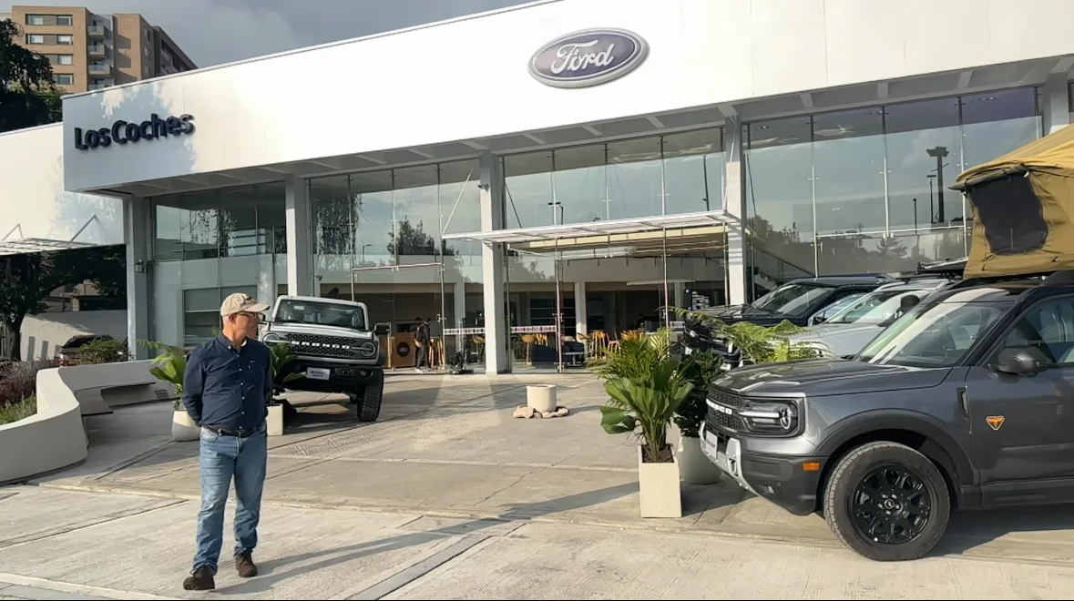 expansión de Ford: Persona frente a concesionario Ford con vehículos exhibidos.