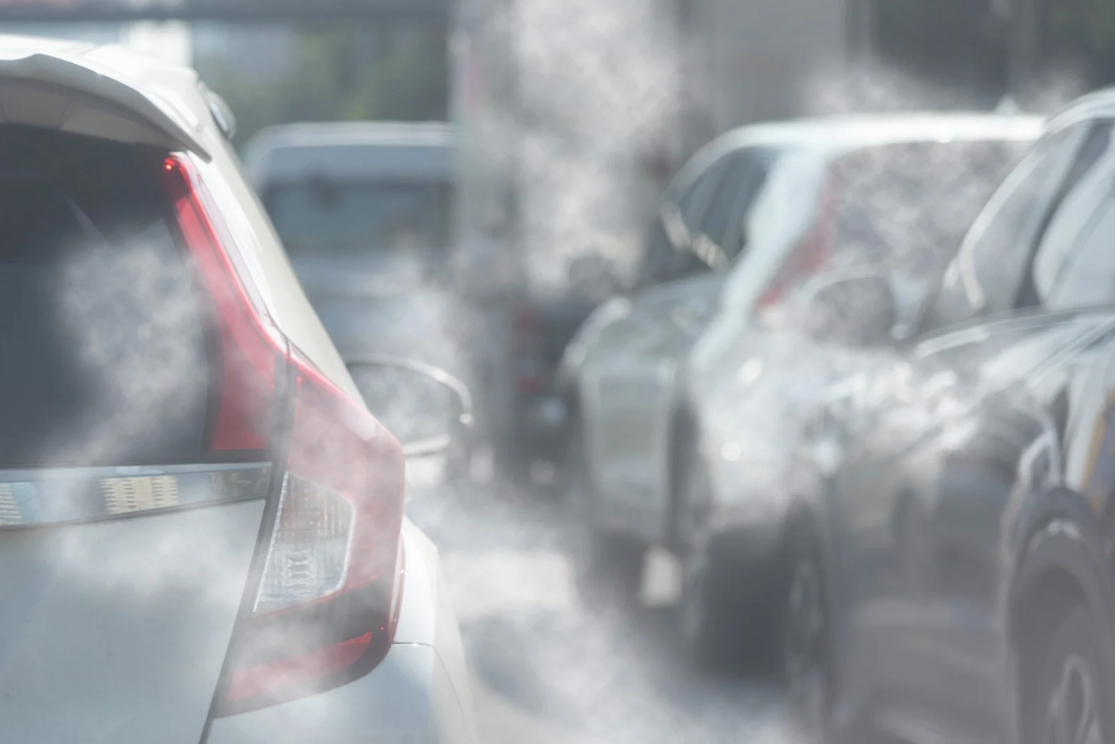 movilidad eléctrica en Geely: Vehículos en tráfico emitiendo humo por el escape.