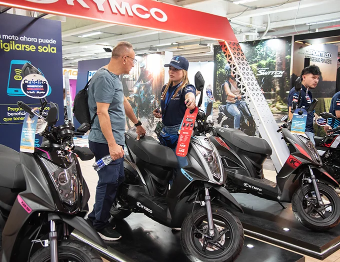 Expo2Ruedas 2026: Cliente observando scooter Kymco Agility 125 en exhibición.