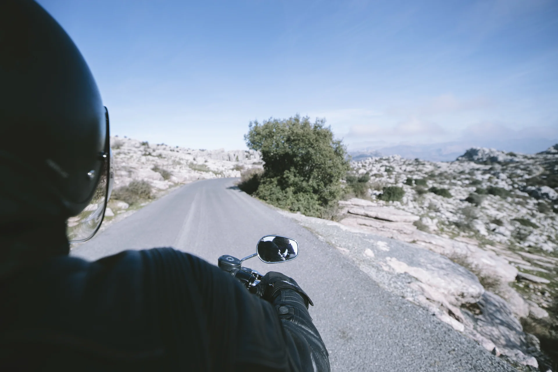 seguridad vial de motocicletas: Motociclista con casco y guantes en carretera montañosa.