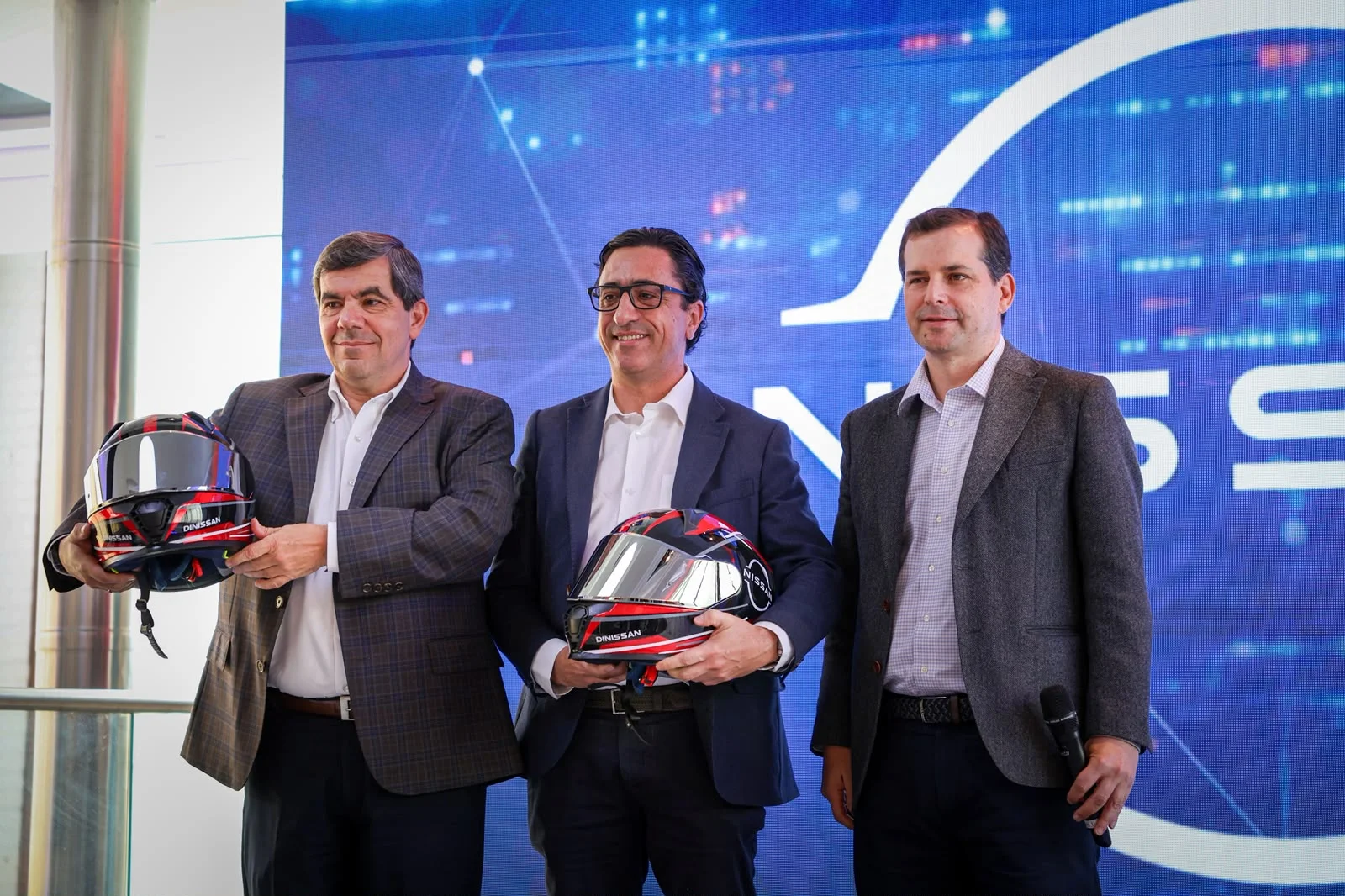 cambios en dirección Nissan: Directivos de Nissan sostienen cascos de carreras.
