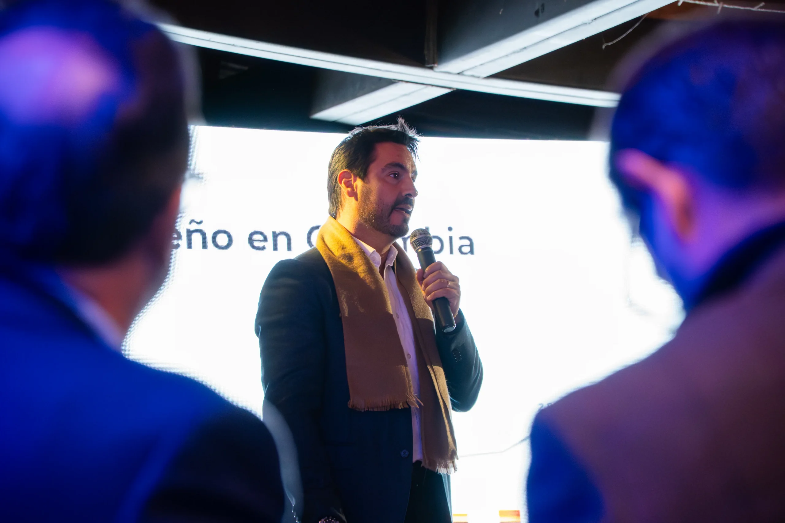Peugeot 2008 Híbrido: Directivo de Peugeot habla en evento con fondo de pantalla.