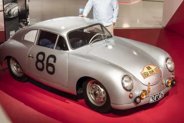 Porsche 356 SL plateado con dorsal 86 y persona.