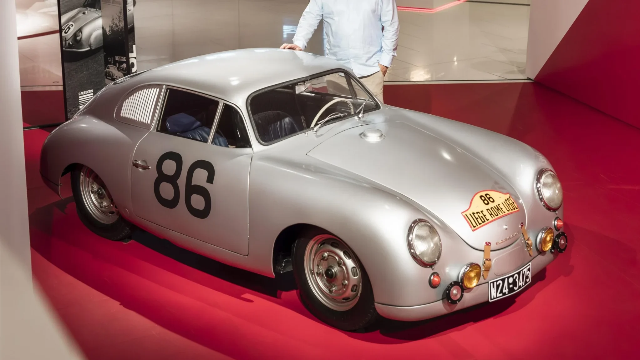 Porsche 356 SL plateado con dorsal 86 y persona.