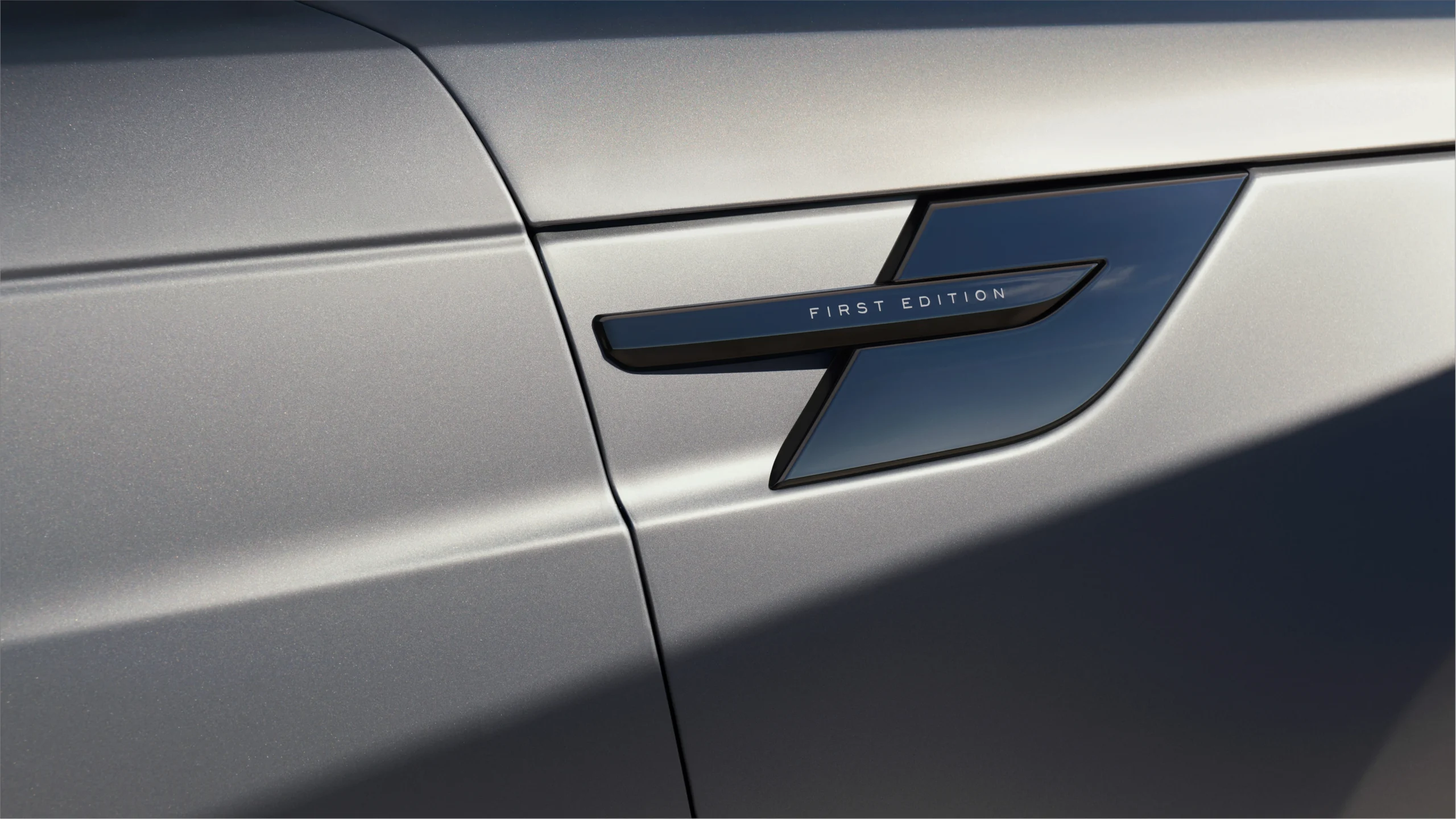 Range Rover Sport Electric: potencia y agilidad en un SUV de lujo electrificado 8 Range Rover Sport Electric: Detalle de emblema First Edition en un Range Rover Sport gris.