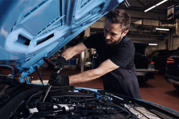resultados de Inchcape: Técnico de servicio revisa motor de carro azul.