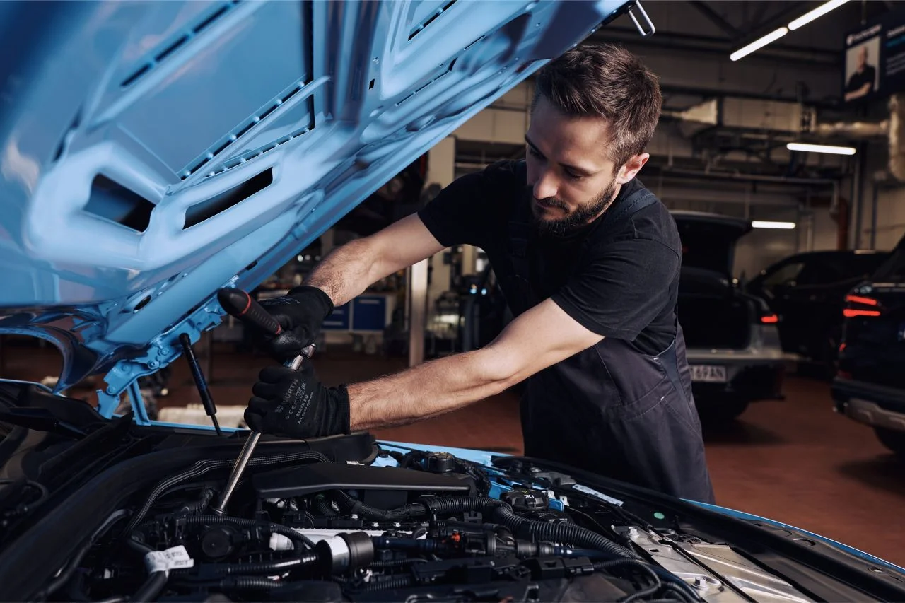 resultados de Inchcape: Técnico de servicio revisa motor de carro azul.