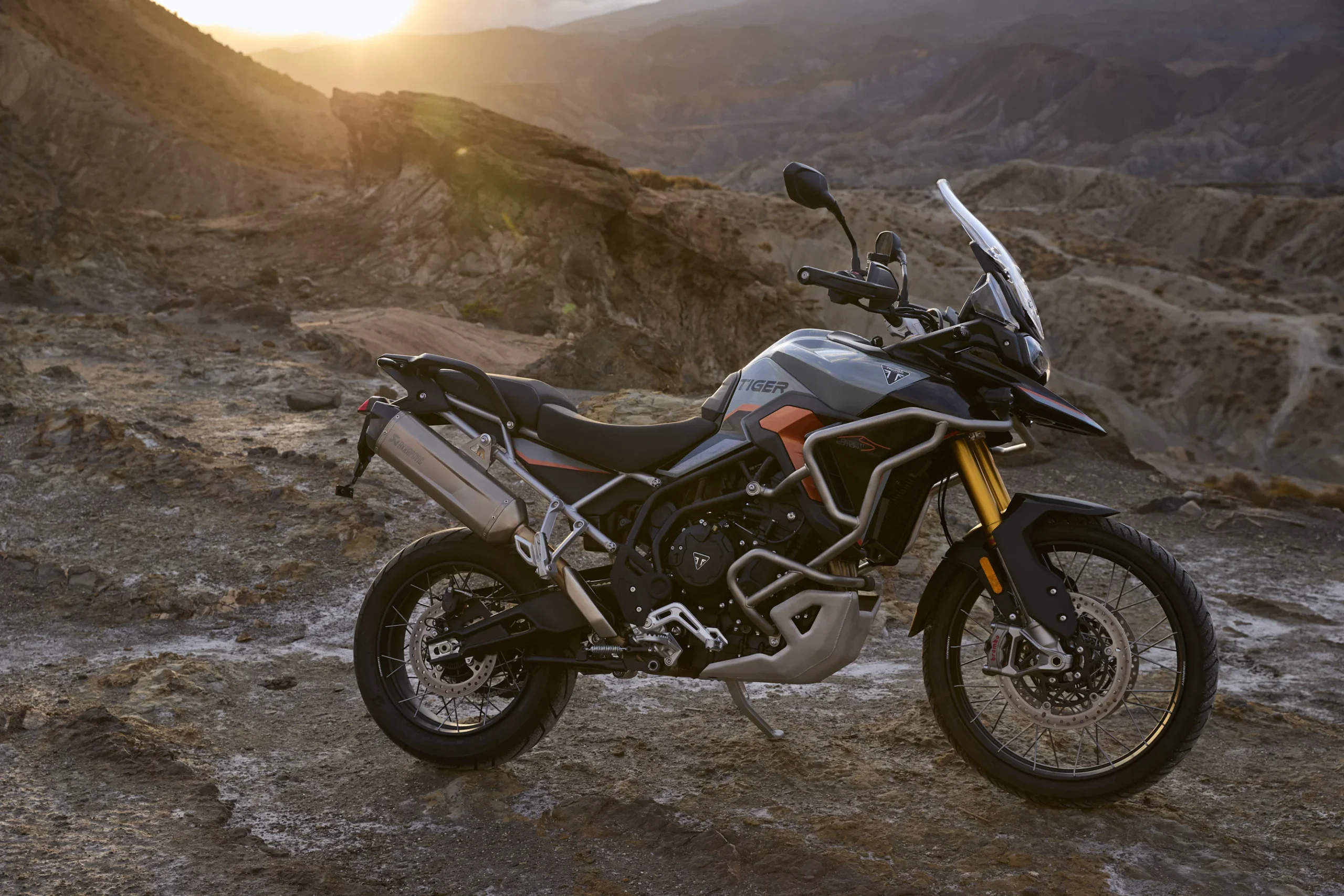 Triumph Tiger 900 Desert Edition en paisaje montañoso árido.